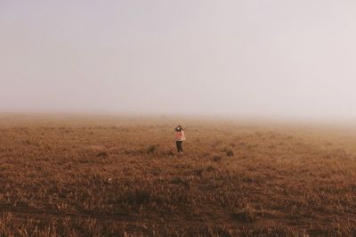 Woman standing on field against sky