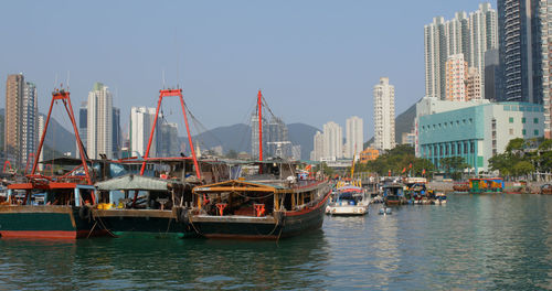 Sailboats moored in sea against buildings in city