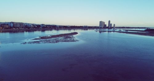 Scenic view of river by buildings against clear sky