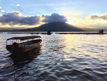 Boats in sea at sunset