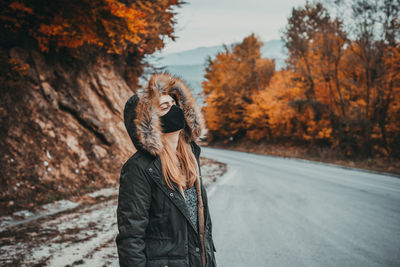 Woman with mask standing on the road during autumn