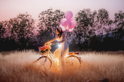 View of person holding balloons on field against sky