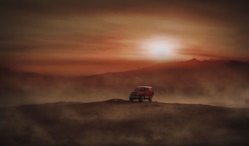 Car on land against sky during sunset