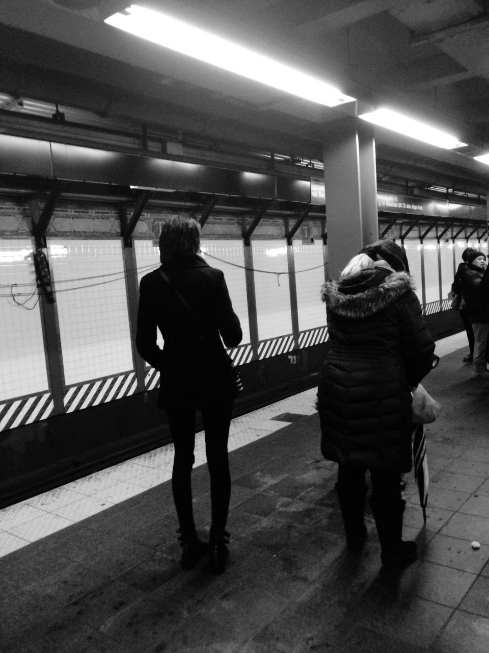 full length, indoors, rear view, lifestyles, walking, men, illuminated, person, railroad station, standing, transportation, leisure activity, railroad station platform, casual clothing, public transportation, passenger, travel