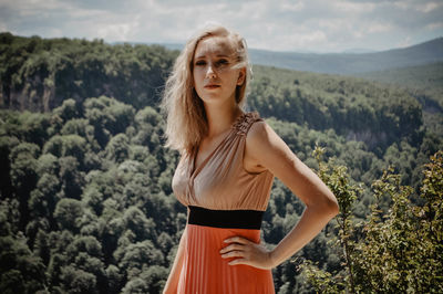 Portrait of beautiful woman standing by landscape