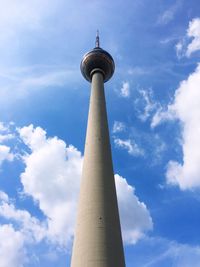 Low angle view of communications tower against cloudy sky