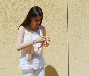 Full length of a young woman standing against wall