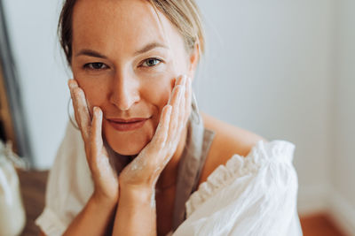 Close up of woman with flour on hands in kitchen, looking at camera