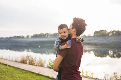 Side view of boy standing against lake