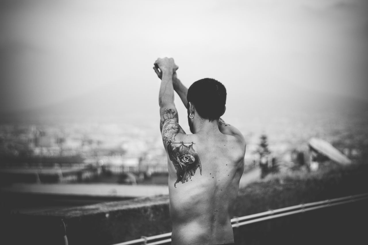 Rear view of shirtless man standing against sky