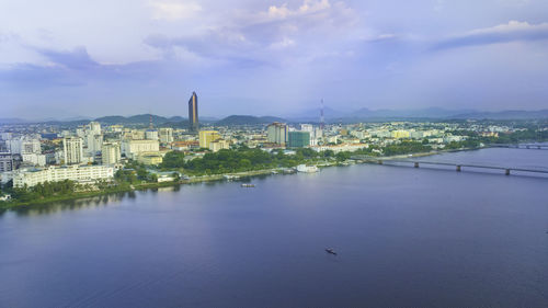 City by river and buildings against sky