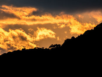 Low angle view of silhouette landscape against dramatic sky