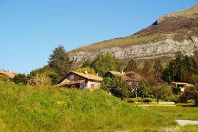 Houses by trees and mountains against clear sky