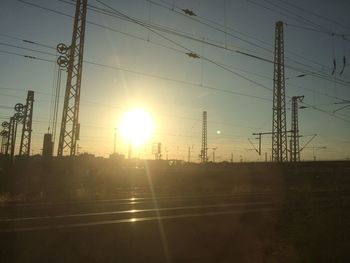 Silhouette electricity pylons against clear sky during sunset