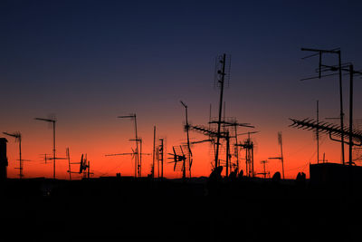 Silhouette antennas against clear sky at sunset