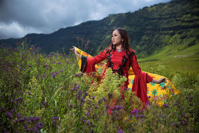 Woman standing on field by mountain against sky