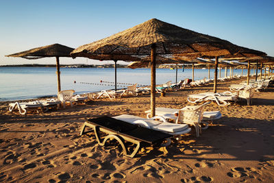 Deck chairs on beach against sky