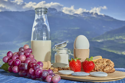 Close-up of fruits with vegetables on table against mountain