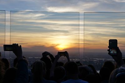 Group of people photographing at sunset