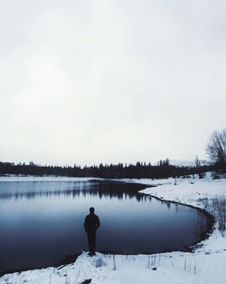 Rear view of man standing in lake against clear sky