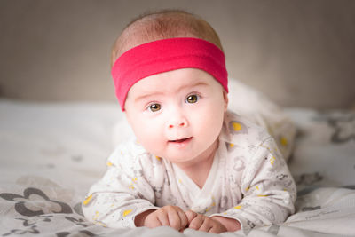 Portrait of cute baby girl lying on bed at home