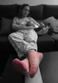 Midsection of woman sitting on sofa at home