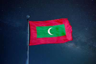 Low angle view of maldives flag against star field sky