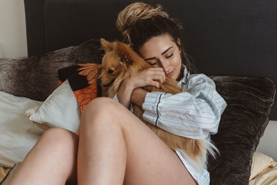 Midsection of young woman with cat relaxing on sofa