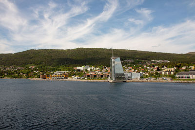 Building by sea against cloudy sky