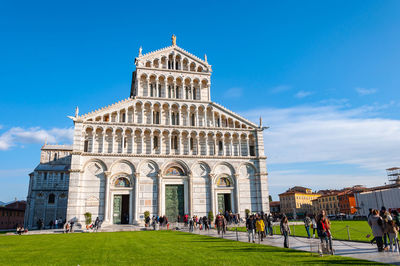 People visiting cathedral against blue sky during sunny day