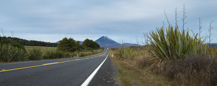 Road leading towards mountains against sky