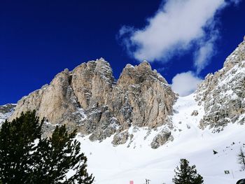 Low angle view of snowcapped mountains against blue sky