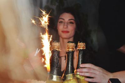 Thoughtful woman with sparks and champagne bottles during celebration