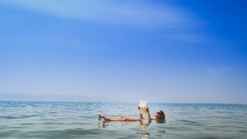 Scenic view of woman floating in the red sea while reading