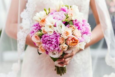 Midsection of bride holding bouquet