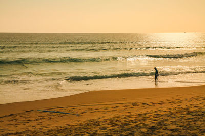 Silhouette person on beach against sky during sunset