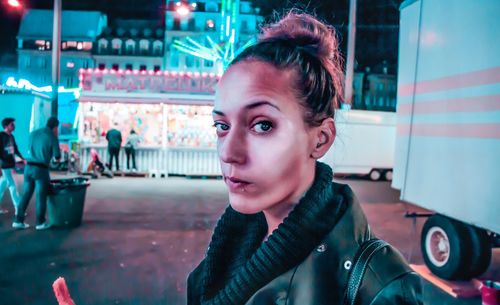 Close-up portrait of young woman in city at night