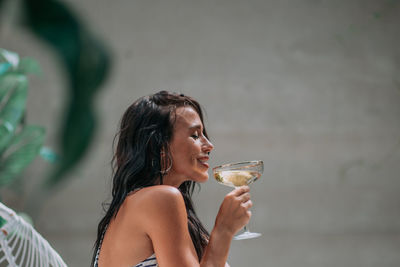 Young woman drinking glass while holding drink