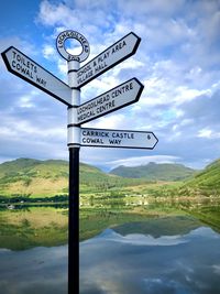 Information sign by lake against sky