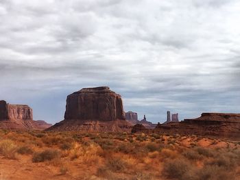 Rock formations on landscape against cloudy sky