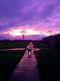 People walking on road against cloudy sky