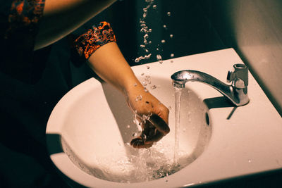 Cropped image of woman washing hands in sink