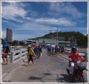 People walking on road against cloudy sky