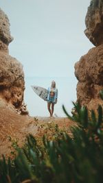 Portrait of young woman with surfboard standing at beach