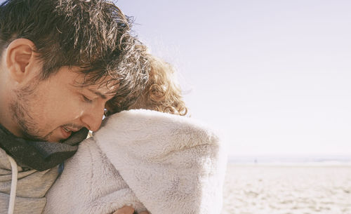 Smiling man embracing daughter at beach