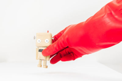 Close-up of hand holding toy over white background