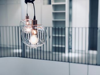 Close-up of illuminated light bulb hanging from ceiling