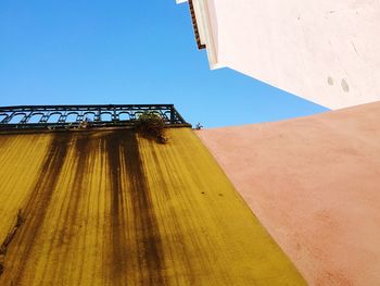 Low angle view of stained wall of house against blue sky