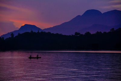 Silhouette boat on lake against sky during sunset