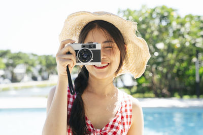 Portrait of woman photographing by swimming pool